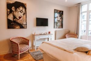 a bedroom with a bed and two chairs and a tv at Chambre Roméo ou Juliette in Honfleur