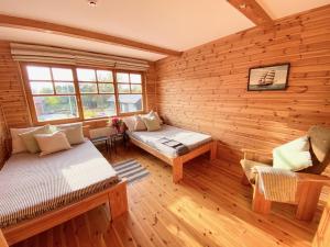 Cabaña de madera con sofá y banco en una habitación en Āķagals, en Pāvilosta
