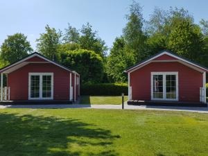 twee rode gebouwen in een park met een tuin bij De Bijsselse Enk, Noors chalet 11 in Nunspeet
