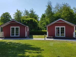 two red buildings in a park with a yard at De Bijsselse Enk, Noors chalet 11 in Nunspeet