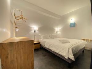 um quarto com uma cama branca e uma cómoda em madeira em Boutique Hôtel Un Appart en Ville em Baiona