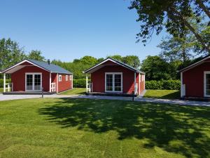 two red cottages in a park with a green lawn at De Bijsselse Enk, Noors chalet 9 in Nunspeet