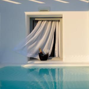 a window with a white curtain and a bottle of wine at Antoperla Luxury Hotel & Spa in Perissa