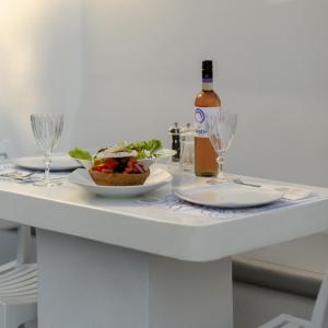a table with a plate of food and a bottle of wine at Antoperla Luxury Hotel & Spa in Perissa