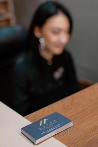 Una donna seduta a un tavolo con un libro blu di Sajam Garni hotel a Leskovac