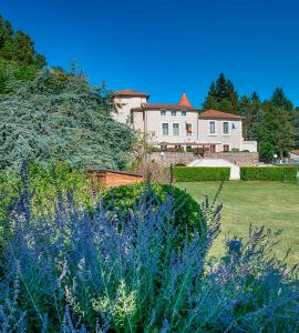 a large white house with a yard with purple flowers at Chateau de Collonges in Saint-Donat-sur-lʼHerbasse