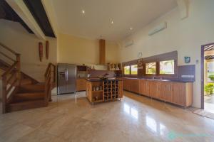 a large kitchen with wooden cabinets and a stainless steel refrigerator at Villa Lumba Lumba - When perfection isn't enough! in Bubunan