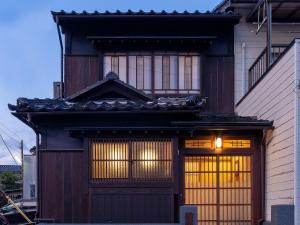 Cette maison dispose d'une grande porte en bois et de fenêtres. dans l'établissement Kurohoro Machiya House, à Kanazawa