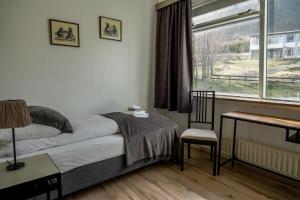 a bedroom with a bed, desk, chair and window at Harbour Inn - Guesthouse in Bíldudalur