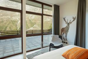 - une chambre dotée d'une grande fenêtre avec un cerf sur le mur dans l'établissement BASE CAMP alpine apartments, à Breuil-Cervinia