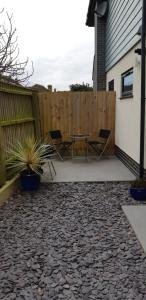 un patio con mesa y sillas junto a una valla en Cliff Top Studio, en Barton-on-Sea