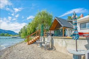 uma casa com cadeiras e um guarda-sol junto à água em Lake Level Cottages em Oroville
