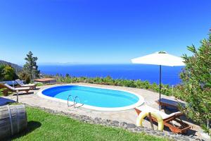 a swimming pool with an umbrella and the ocean at Casa Lorenzo in Tijarafe