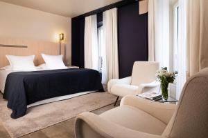 パリにあるオテル ド ネルのベッド1台と椅子2脚が備わるホテルルームです。
