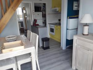 a kitchen with a table and a stove and a refrigerator at joli duplex proche commerces et mer in Stella-Plage