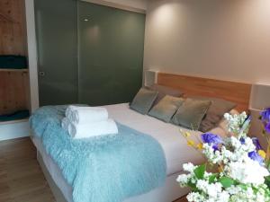 a bedroom with a bed with a blue blanket and flowers at Hotel Rural Aguazul in Covanera