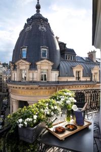 a table with food and flowers on a balcony with a building at Hotel de Nell in Paris