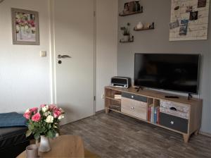 a living room with a television and a table with flowers at de lütte Kabuff in Born