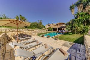 un patio con sillas, una sombrilla y una piscina en Villa Marina Cabanellas, en Pollensa