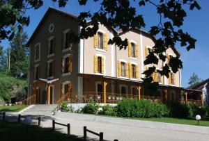 - un grand bâtiment avec des portes et des fenêtres jaunes dans l'établissement Logis - Hotel Restaurant du Parc, à Cransac