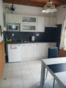 a kitchen with white cabinets and a sink and a table at Ubytování Maxa in Špičák