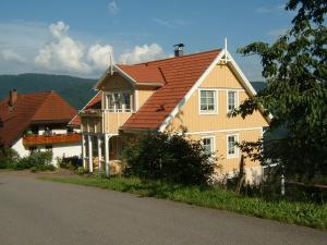 une maison jaune avec un toit rouge dans une rue dans l'établissement Schwedenhaus Raich, à Kleines Wiesental