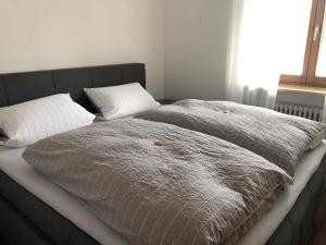 a bed with a gray comforter and two pillows at Gästehaus Aurikel 10 in Fischen