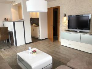 a living room with a television and a white table at Gästehaus Aurikel 10 in Fischen