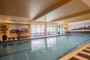 a large swimming pool in a large room with windows at Fletcher Hotel-Restaurant De Buunderkamp in Wolfheze