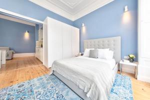 Dormitorio azul con cama blanca y pared azul en Aveiro History Apartments, en Aveiro