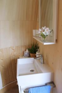 een wastafel in de badkamer met een vaas met bloemen erop bij Igluhut Tiny House Bayerischer Wald in Zachenberg