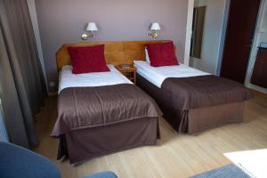 two beds in a hotel room with red pillows at Hotel Terraza in Ljungby