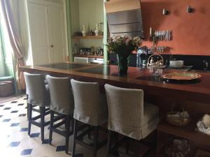 a kitchen with a large wooden island with bar stools at La Grande Maison in Seine-Port