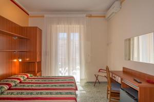 una camera con letto, scrivania e finestra di Hotel Dolly a Viareggio