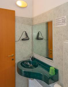 W łazience znajduje się zielona umywalka i lustro. w obiekcie Hotel Dolly w Viareggio