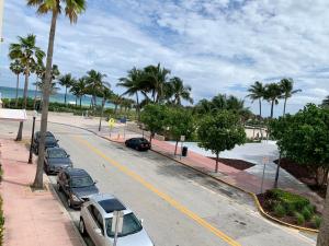 a street with parked cars and palm trees on a beach at Dream Studio on the Beach in Miami Beach