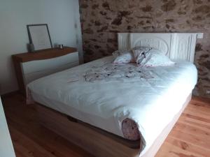 um quarto com uma cama branca e uma parede de pedra em Chambre d'hôtes en Segala em La Salvetat-Peyralès