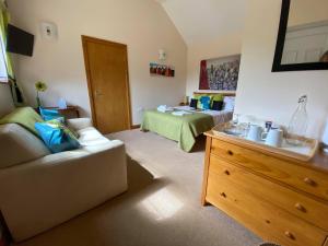 a bedroom with a bed and a couch and a dresser at High View Cottage in Uttoxeter