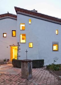 un edificio blanco con una cruz delante de él en B&B La Rectoria de Sant Miquel de Pineda, en Sant Feliu de Pallerols