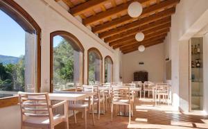 un comedor con mesas, sillas y ventanas en B&B La Rectoria de Sant Miquel de Pineda, en Sant Feliu de Pallerols