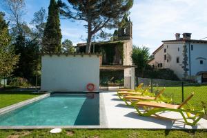una piscina con sillas y una casa en el fondo en B&B La Rectoria de Sant Miquel de Pineda, en Sant Feliu de Pallerols