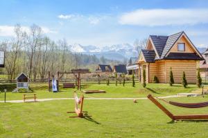 a yard with chairs and a house and mountains at Domki Gawra in Zakopane