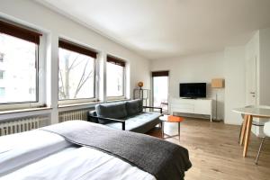 a bedroom with a bed and a couch and windows at Arthouse Apartments im Pantaleonsviertel in Cologne