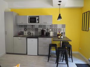 Una cocina con electrodomésticos blancos y una mesa con taburetes. en Le Millotet - Agréable studio à 2 mn Dijon Gare, en Dijon