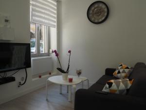 sala de estar con sofá, mesa y reloj en Le Millotet - Agréable studio à 2 mn Dijon Gare, en Dijon