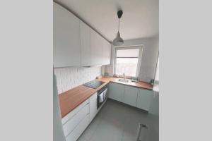 a kitchen with white cabinets and a sink and a window at Seaview Apartament z Balkonem i Widokiem na Morze in Sopot