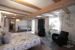 ein Schlafzimmer mit einem Bett und zwei Stühlen darin in der Unterkunft 5 Sterne Ferienhaus Gut Stohrerhof am Ammersee bis 15 Personen in Dießen am Ammersee