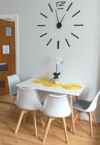 stół i krzesła z zegarem na ścianie w obiekcie Mieszkanie u Dominiki INPIW01 w mieście Piwniczna