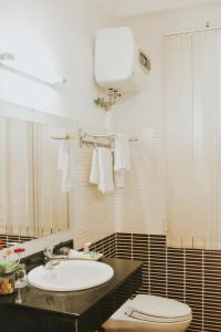 uma casa de banho com um lavatório branco e um WC. em Hue Harmony Hotel em Hue