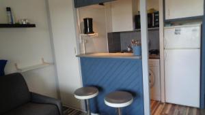 una pequeña cocina con encimera y taburetes en una habitación en Appt Dolus-d'Oléron, Vert bois 2-3 personnes en Grand-Village-Plage